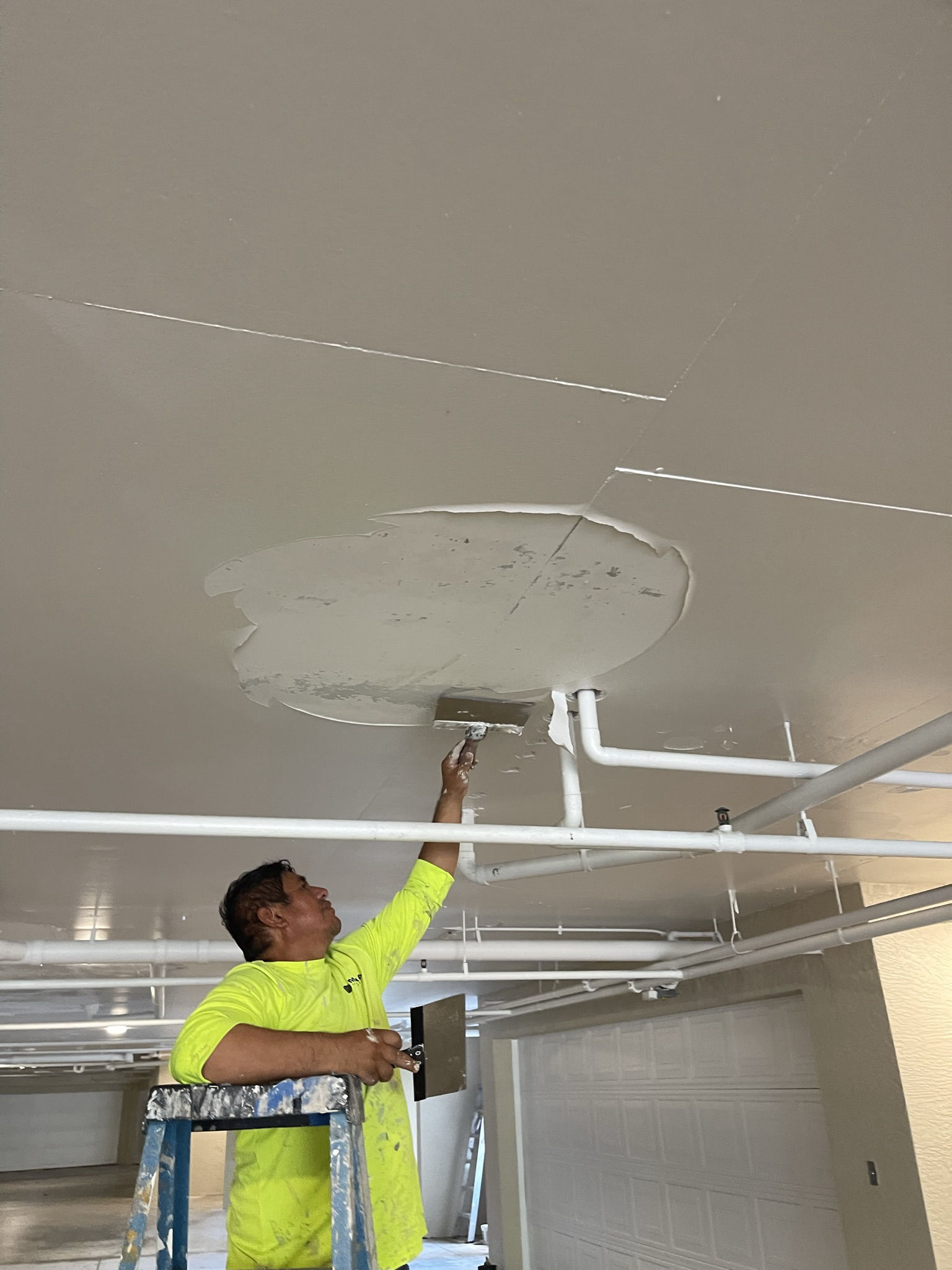 MORA painter coating a parking garage ceiling at The Crescent at Pelican Bay, Naples